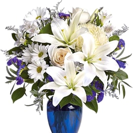 White lilies and daisies arranged in a blue vase