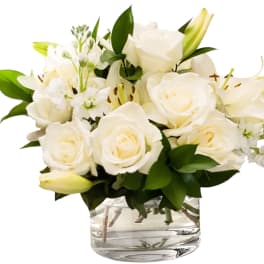White roses and lilies arranged in a clear glass vase
