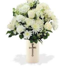 White floral arrangement in a cream vase with a cross emblem