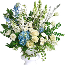 White and blue floral arrangement in a white pedestal vase