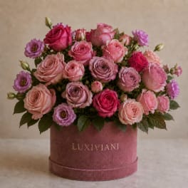 Pink and lavender roses arranged in a round hatbox