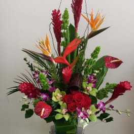 Tall tropical flower arrangement in a decorative pedestal vase