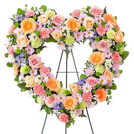 Heart-shaped floral wreath on a black easel with pink, peach, and orange blooms