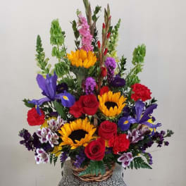 Colorful mixed flower arrangement in a wicker basket on a pedestal