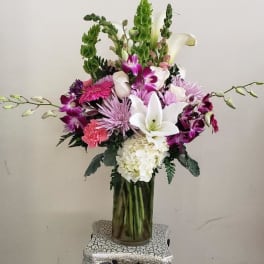 Tall mixed bouquet in a glass vase with white lilies and purple flowers