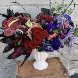 Bold mixed bouquet in a white vase with red, purple, and blue flowers