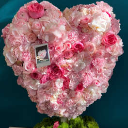 Heart-shaped pink floral arrangement in a box with a ribbon