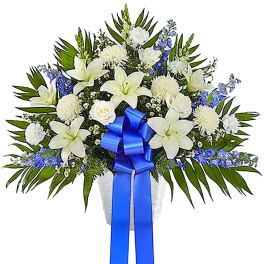 White lilies and chrysanthemums with blue ribbon in a vase