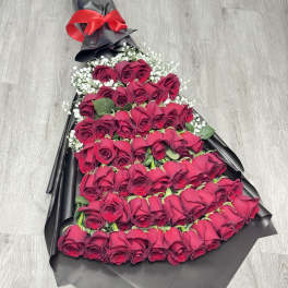 Large bouquet of red roses wrapped in black paper with a red bow