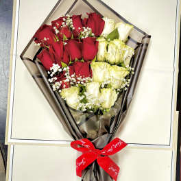 Bouquet of red and white roses wrapped in dark paper with a red ribbon