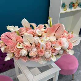 Large pastel bouquet of pink roses and white calla lilies in a white bowl