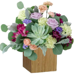 Mixed bouquet in a wooden box with roses, carnations, and succulents