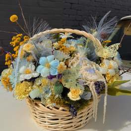 Basket arrangement with pastel flowers and decorative butterflies