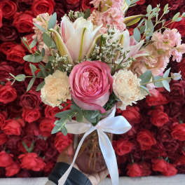 Pink and white bouquet in a glass vase with a white ribbon
