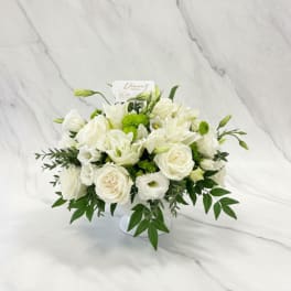 White floral arrangement in a low vase with green accents