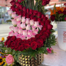 Tiered arrangement of red and pink roses in a gold vase