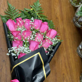 Bouquet of pink roses wrapped in black paper with a pink ribbon