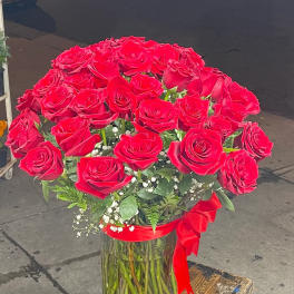 Bouquet of red roses in a clear glass vase with a red ribbon