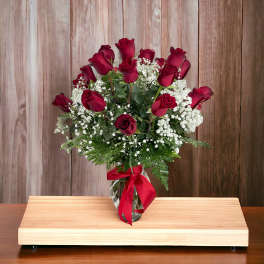 Red roses in a glass vase with white baby's breath and a red ribbon