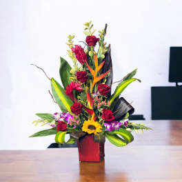 Tall tropical bouquet with red roses and a sunflower in a red vase