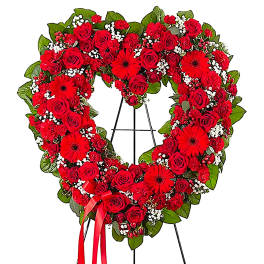 Heart-shaped red rose wreath on a black easel with a red ribbon