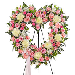 Heart-shaped floral wreath on an easel with pink and white flowers