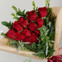 Bouquet of red roses wrapped in tan paper with greenery