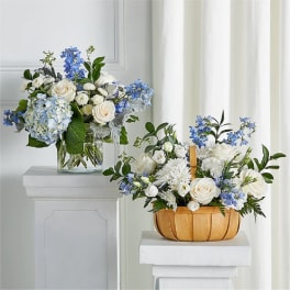 Two blue and white floral arrangements in glass and wooden containers