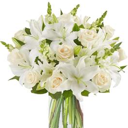 White lilies and cream roses in a clear glass vase