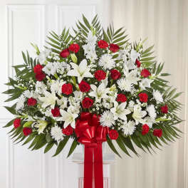 Large standing spray of red and white flowers with a red ribbon