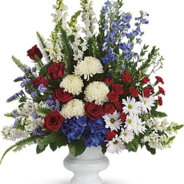 Large mixed flower arrangement in a white pedestal vase