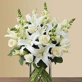 White lilies and roses arranged in a clear glass vase