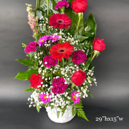 Tall mixed bouquet with red roses and pink gerbera daisies in a white basket