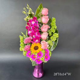 Pink roses, orchids, and daisies arranged in a purple vase