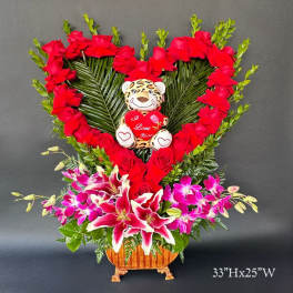 Heart-shaped rose arrangement with a teddy bear and lilies in a basket