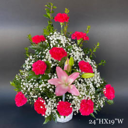 Pink lilies and carnations in a white basket with baby's breath