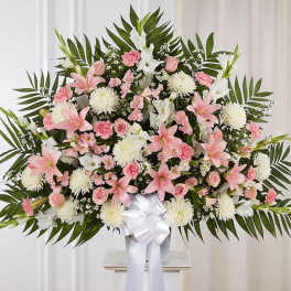 Large pink and white floral spray in a vase with a white ribbon