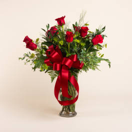 Red roses in a clear glass vase with a large red ribbon