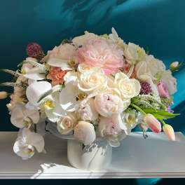Pastel bouquet of roses, peonies, and orchids in a white vase