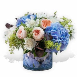 Blue and blush flowers arranged in a glass vase