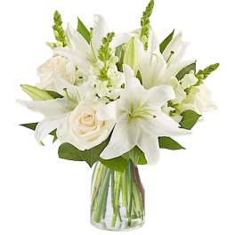 White lilies and roses arranged in a clear glass vase