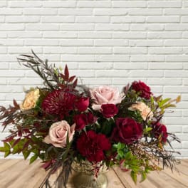 Mixed bouquet of red and blush roses in a gold vase