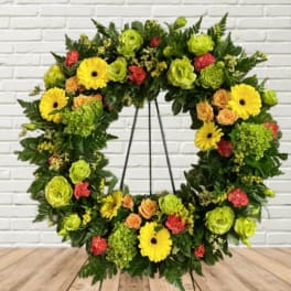 Floral wreath with yellow gerbera daisies, green blooms, and peach roses