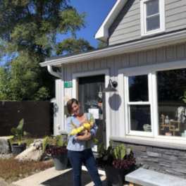 Woman holding a yellow flower bouquet outside a house