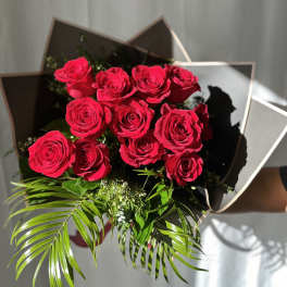 Bouquet of red roses with palm fronds and dark wrapping