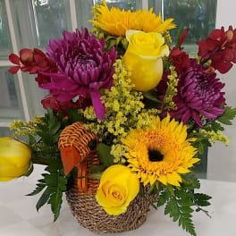 Basket arrangement with yellow roses, sunflowers, and purple chrysanthemums