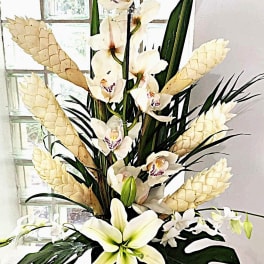 Tall arrangement of white orchids and lilies with pale cone accents