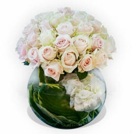Bouquet of pale pink and white roses in a round glass vase