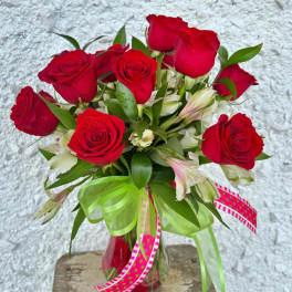 Red roses in a glass vase with pink ribbons