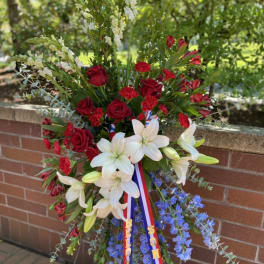Standing floral spray with red roses, white lilies, and blue flowers